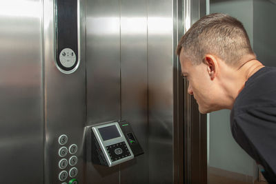 Side view of man looking through window