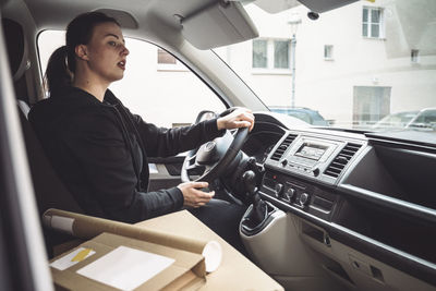 Delivery woman with package driving truck