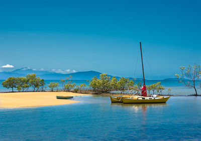 Sailboats moored on sea against blue sky