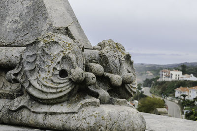 Close-up of statue against historic building against sky