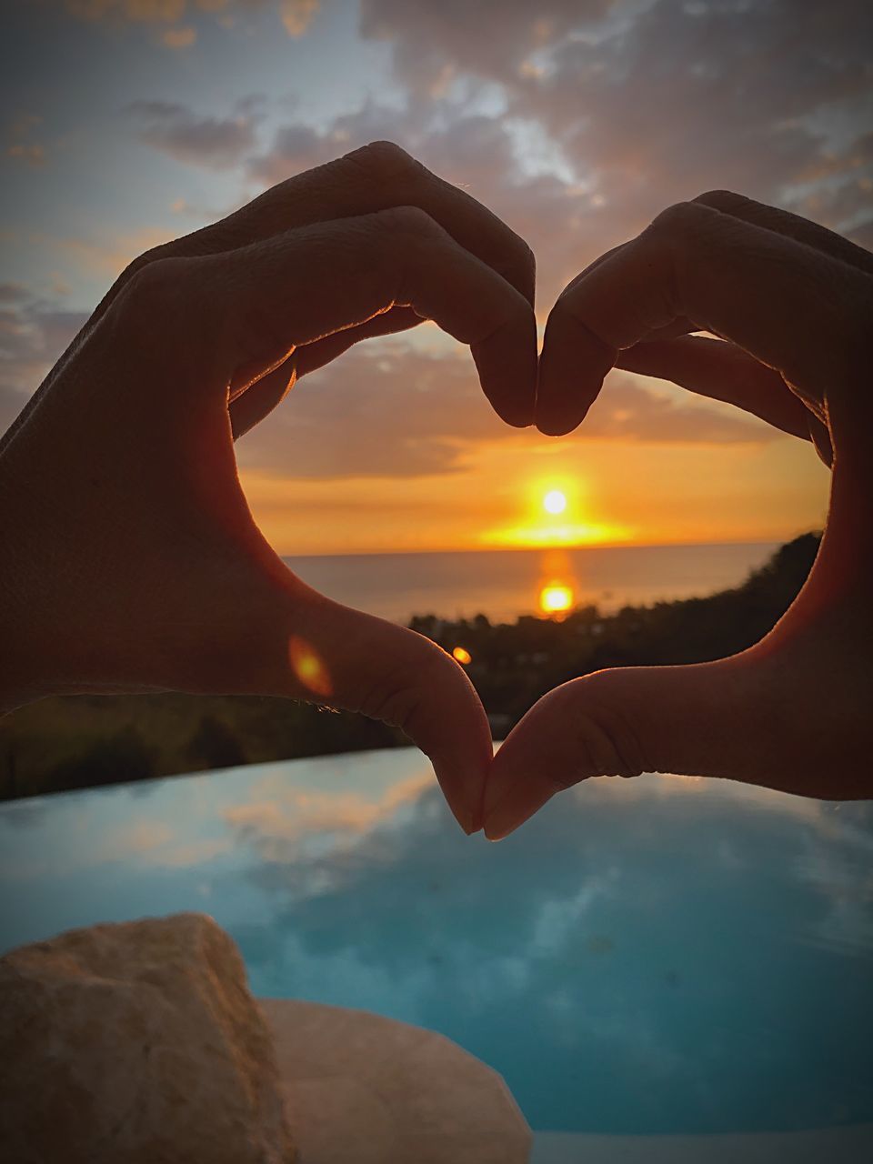 CLOSE-UP OF HAND HOLDING HEART SHAPE AGAINST SKY DURING SUNSET