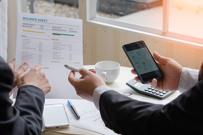 Midsection of woman holding smart phone on table