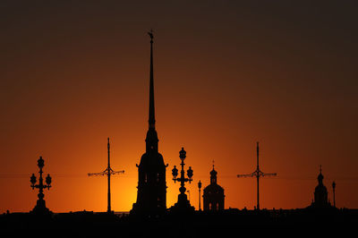 Silhouette cranes against sky during sunset