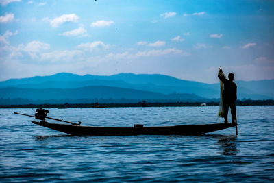 Silhouette man on boat in sea against sky