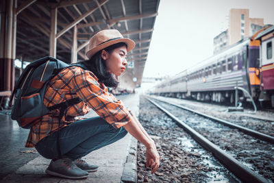 Young woman looking at train at railroad station