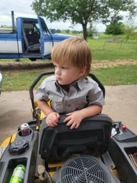 Wyatt sitting on the lawn mower.