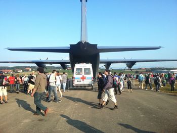 People waiting at airplane against clear sky