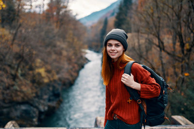 Portrait of young woman standing by tree during autumn