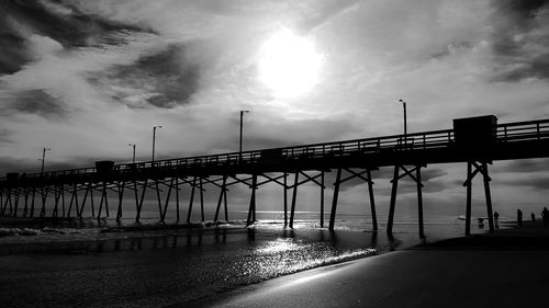 Silhouette pier at beach against sky