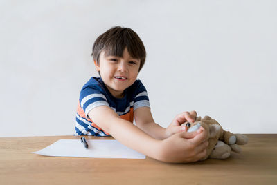 Cute baby boy on table against white background