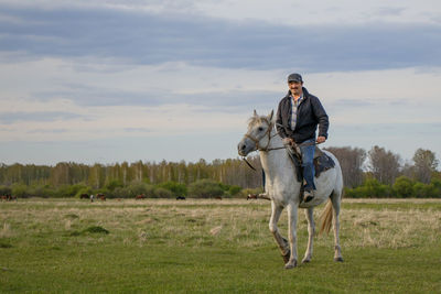 A rider on a white horse in the field