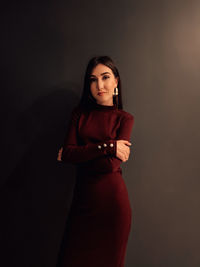 Portrait of woman standing against black background