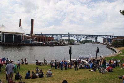 People on bridge over river against sky