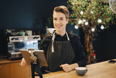 Portrait of smiling woman holding coffee at cafe