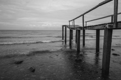 Wooden posts on beach against sky