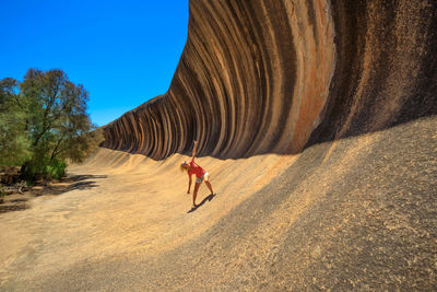 Woman standing with arms outstretched by cliff