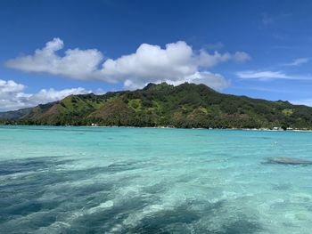 Scenic view of sea and mountains against blue sky