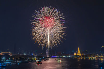 High angle view of river amidst city against firework display in sky at night