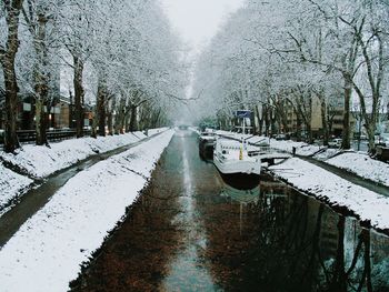 Snow covered canal amidst trees during winter
