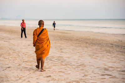 Rear view of men walking on beach