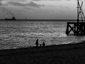 Silhouette people standing on beach against sky