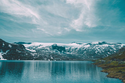 Scenic view of lake and snowcapped mountains against sky