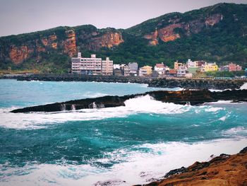 Scenic view of sea by mountains against sky