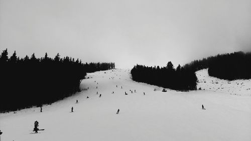 People skiing on snow covered landscape against clear sky