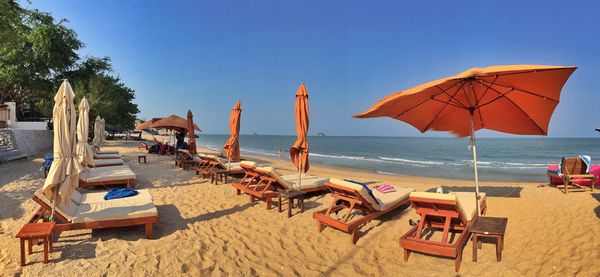 Deck chairs on beach against blue sky