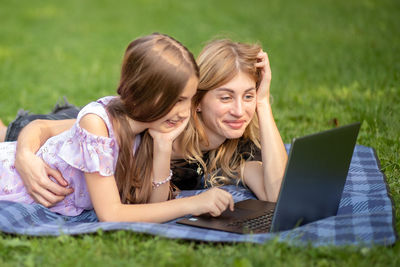 Friends using laptop while sitting on field