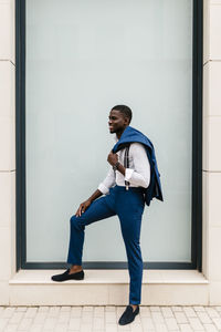 Side view of young man looking away against wall