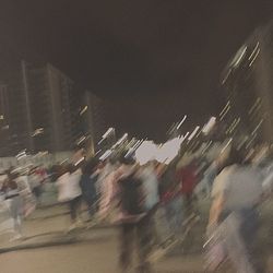 Crowd in city against sky at night