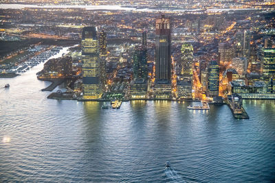 High angle view of illuminated city by sea