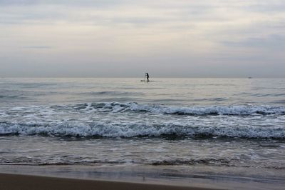 Silhouette person in sea against sky during sunset