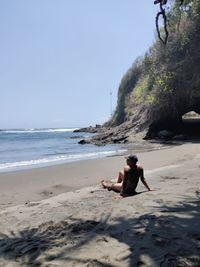 Full length of shirtless boy on beach against sky