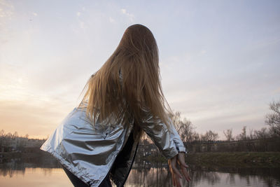 Rear view of woman standing in lake against sky