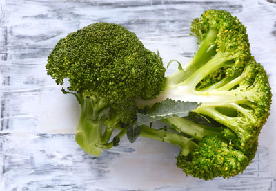 Close up of a halved brocolli head on white wood