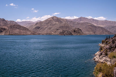 Scenic view of sea and mountains against blue sky