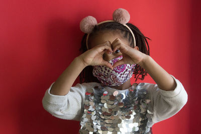 Midsection of woman holding red while standing against wall