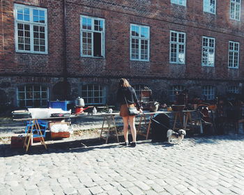 Rear view of young woman with dog shopping at market against building