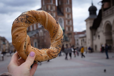 Tourist woman eating bagel obwarzanek traditional polish cuisine snack waling on market square st