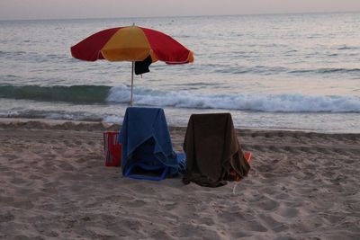 Deck chairs on beach against sky