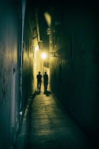 Silhouette people walking on illuminated tunnel