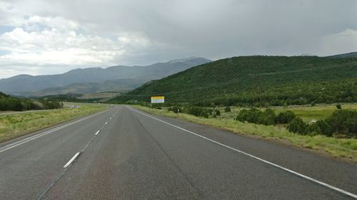 Empty road by mountains against sky