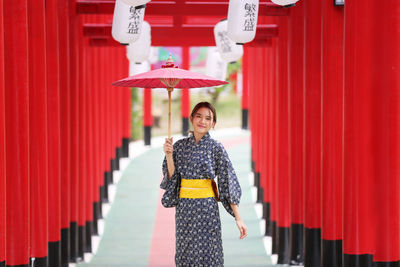 Portrait of woman standing against red wall