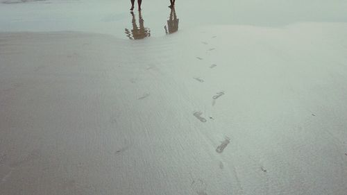 Low section of footprints on sand at beach