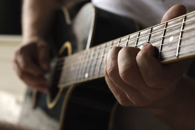 Playing the guitar. strumming acoustic guitar. musician plays music. man fingers holding mediator