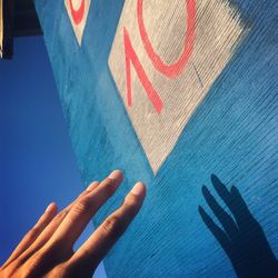 Close-up of human hand against blue wall