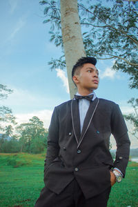 Young man looking away while standing on field