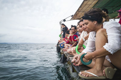 People on boat in sea against sky